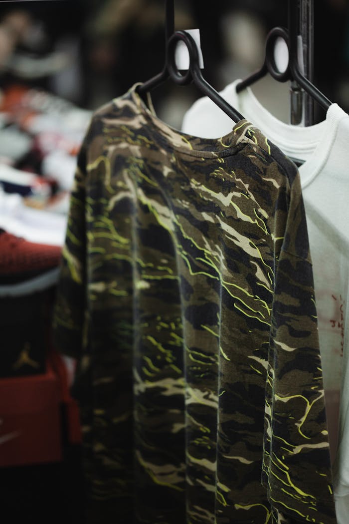 about-03 Close-up of a camouflage T-shirt on a hanger in a retail setting.